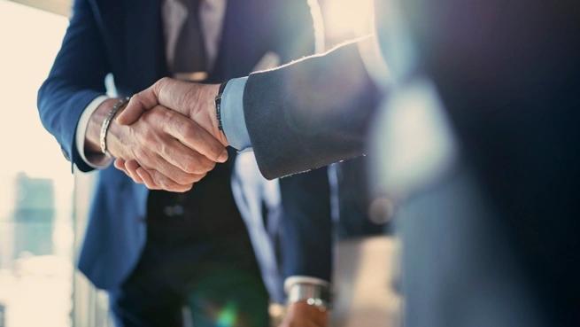 close up of two men in suits shaking hands